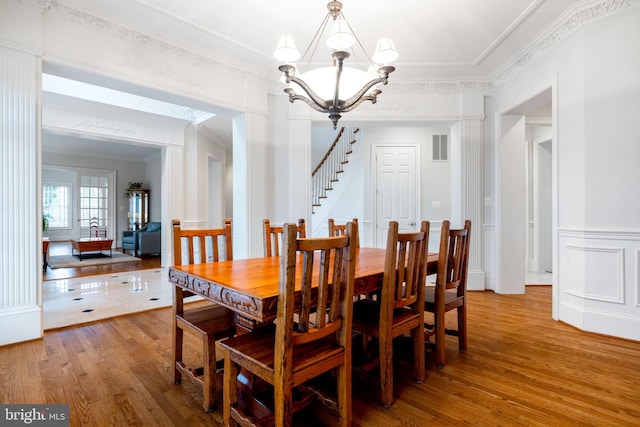 dining space with visible vents, crown molding, a wainscoted wall, an inviting chandelier, and wood finished floors