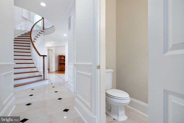 bathroom featuring recessed lighting, tile patterned flooring, wainscoting, a decorative wall, and toilet