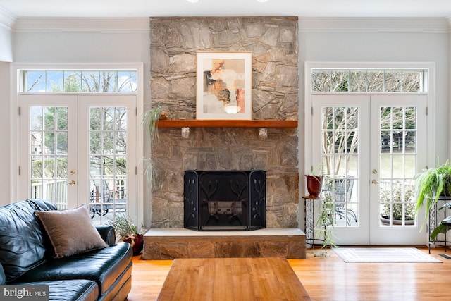 living area with french doors, wood finished floors, ornamental molding, and a fireplace