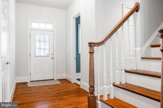 entryway featuring baseboards, wood finished floors, and stairs