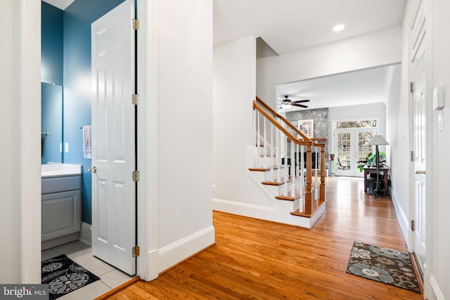 entryway with light wood-style flooring, baseboards, stairs, and ceiling fan