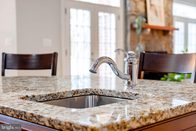 interior details featuring light stone counters and a sink