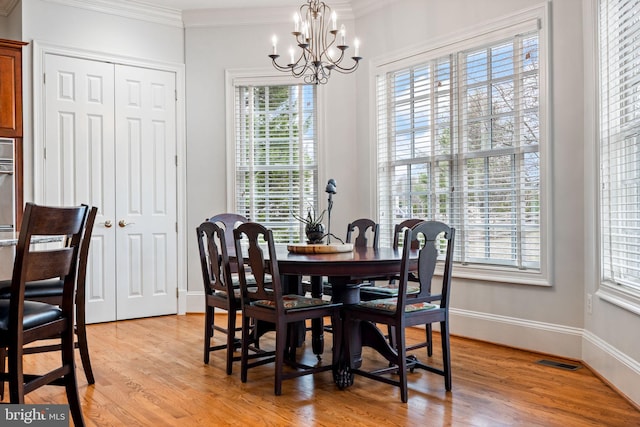 dining area with light wood-type flooring, visible vents, an inviting chandelier, crown molding, and baseboards