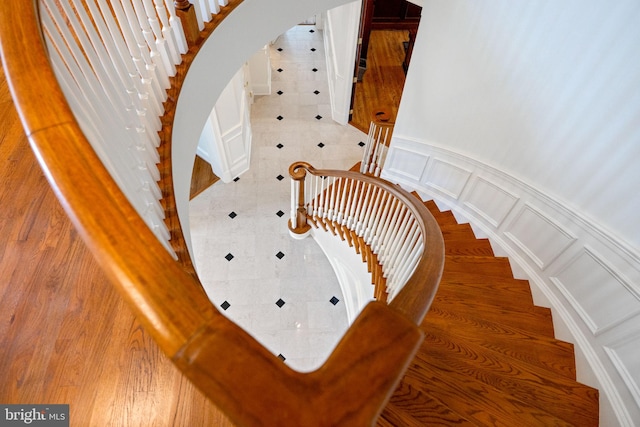 staircase featuring arched walkways, a decorative wall, and wainscoting