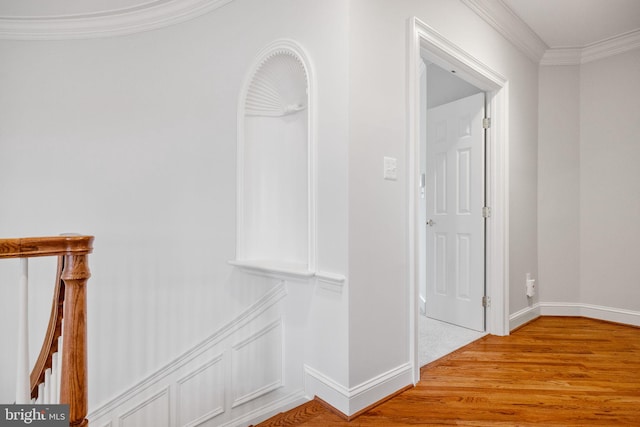 corridor with light wood finished floors, crown molding, and baseboards