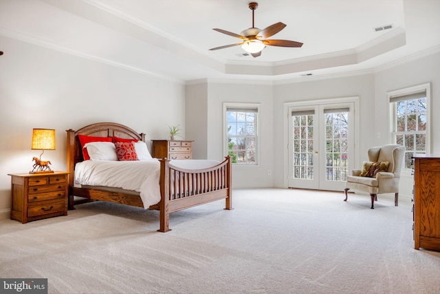 bedroom with visible vents, a tray ceiling, ornamental molding, carpet flooring, and access to outside