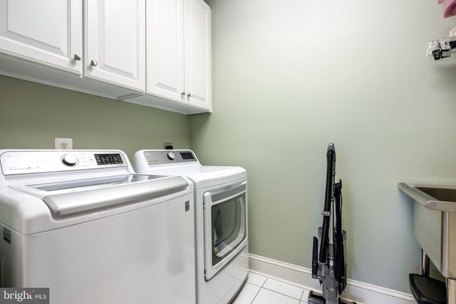 washroom with light tile patterned floors, baseboards, cabinet space, and independent washer and dryer