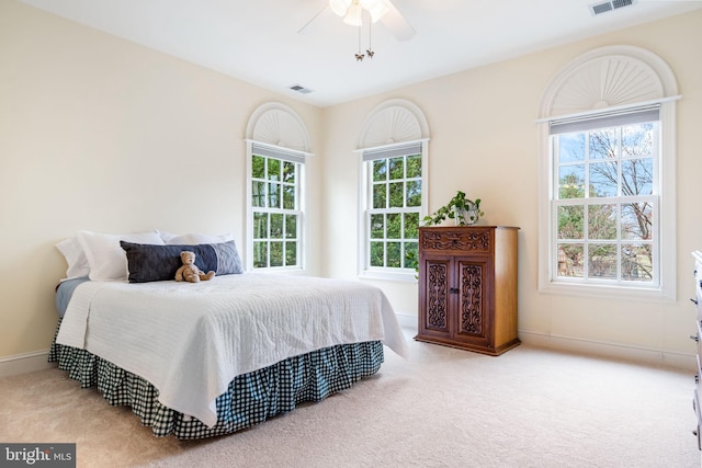 carpeted bedroom with visible vents, baseboards, and ceiling fan