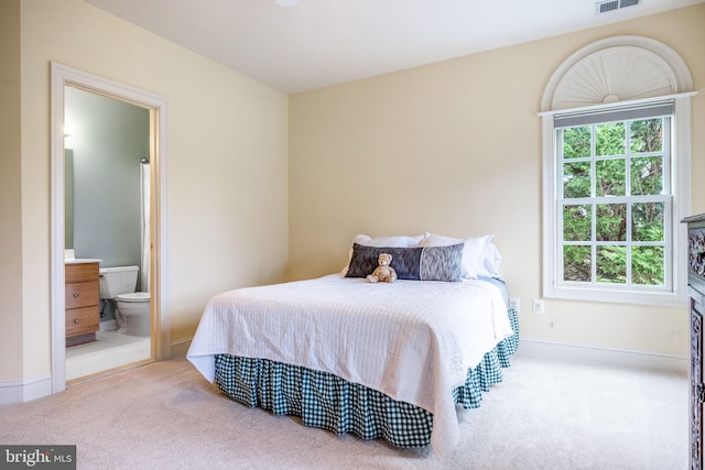 carpeted bedroom with visible vents, baseboards, and ensuite bathroom