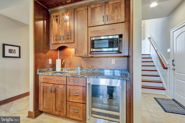 24537 Wave Maker Dr, Millsboro, DE 19966 - kitchen featuring beverage cooler, a sink, stainless steel microwave, dark stone counters, and brown cabinetry