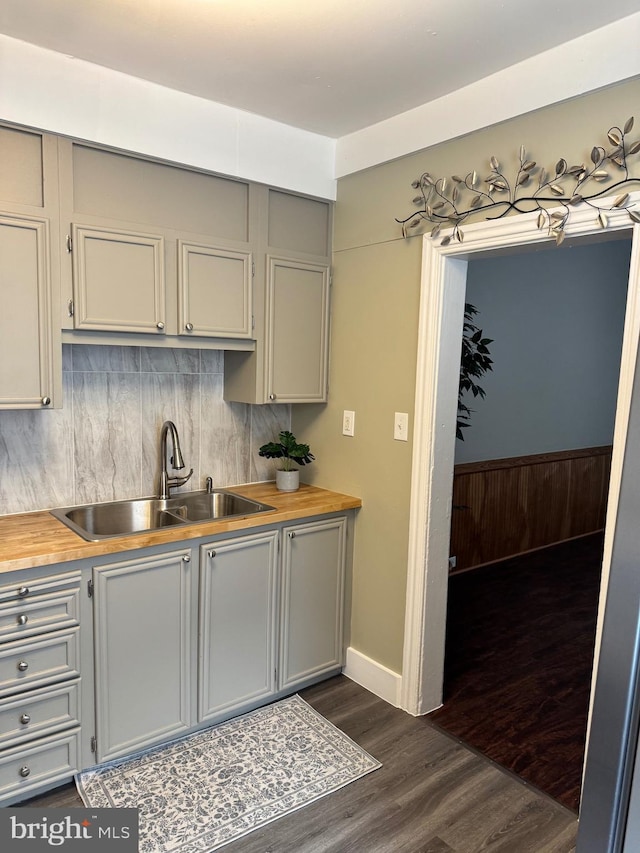 kitchen with a sink, gray cabinets, butcher block counters, and dark wood-style flooring