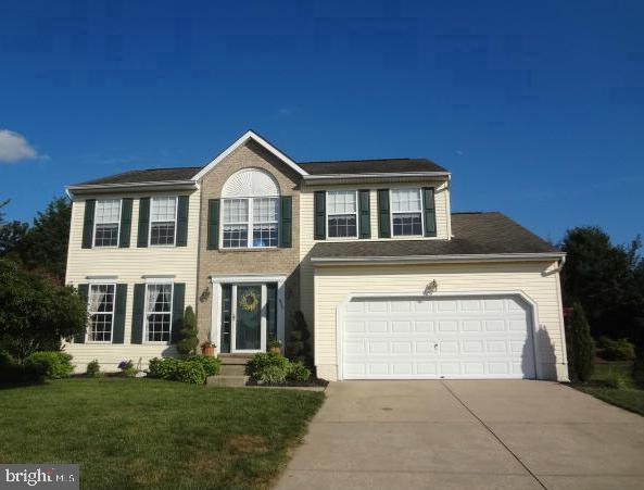 colonial house with concrete driveway and a front lawn