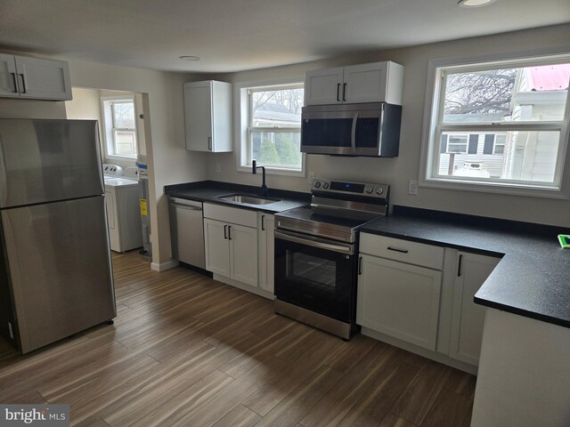 kitchen featuring dark wood-style floors, washing machine and dryer, stainless steel appliances, and a sink