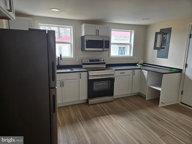 kitchen featuring dark countertops, light wood-type flooring, recessed lighting, appliances with stainless steel finishes, and a sink