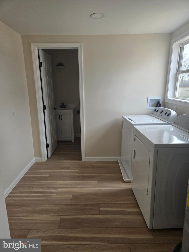 washroom with laundry area, light wood-type flooring, baseboards, and separate washer and dryer