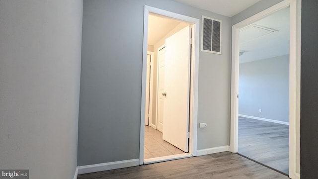 hall featuring visible vents, baseboards, and wood finished floors