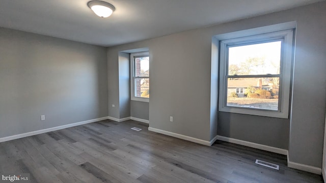 spare room with visible vents, baseboards, and wood finished floors