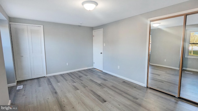 unfurnished bedroom with visible vents, baseboards, and wood finished floors