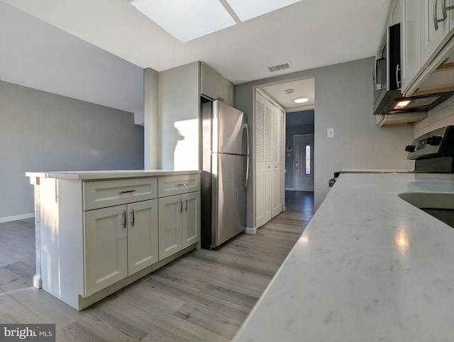 kitchen featuring light stone counters, baseboards, light wood finished floors, visible vents, and appliances with stainless steel finishes