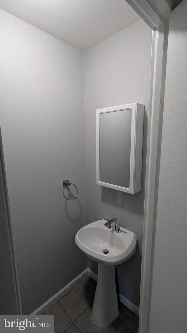 bathroom featuring tile patterned flooring, baseboards, and a sink