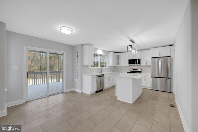 kitchen with backsplash, white cabinetry, stainless steel appliances, light countertops, and glass insert cabinets