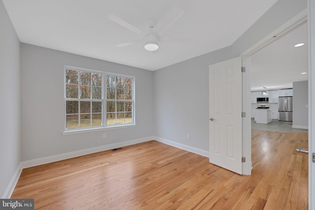 unfurnished room featuring light wood-type flooring, baseboards, visible vents, and ceiling fan