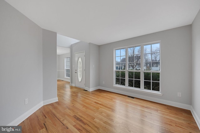 empty room with visible vents, baseboards, and light wood finished floors