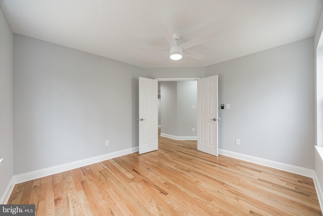 empty room with light wood-style flooring, a ceiling fan, and baseboards