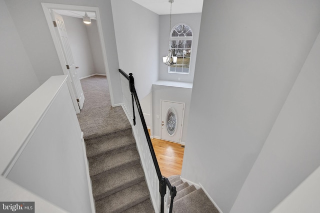 staircase with baseboards, carpet, and an inviting chandelier