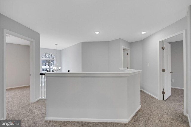 interior space featuring a chandelier, hanging light fixtures, light colored carpet, and baseboards