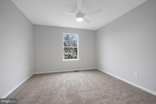 carpeted spare room with visible vents, baseboards, and ceiling fan