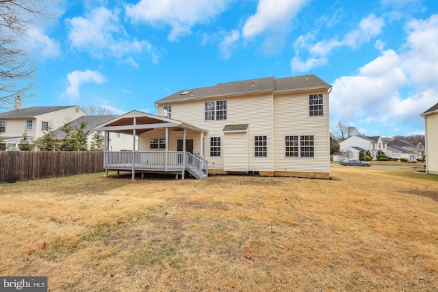 rear view of house with a lawn, a deck, and fence