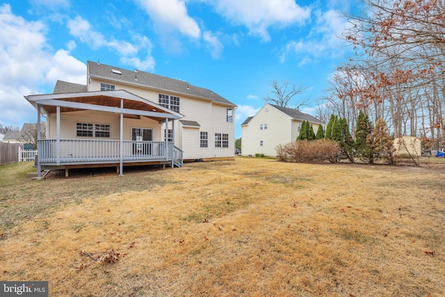 rear view of property with a yard, roof with shingles, and a wooden deck