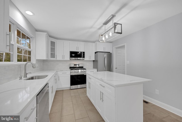 kitchen featuring a sink, light stone counters, tasteful backsplash, appliances with stainless steel finishes, and glass insert cabinets