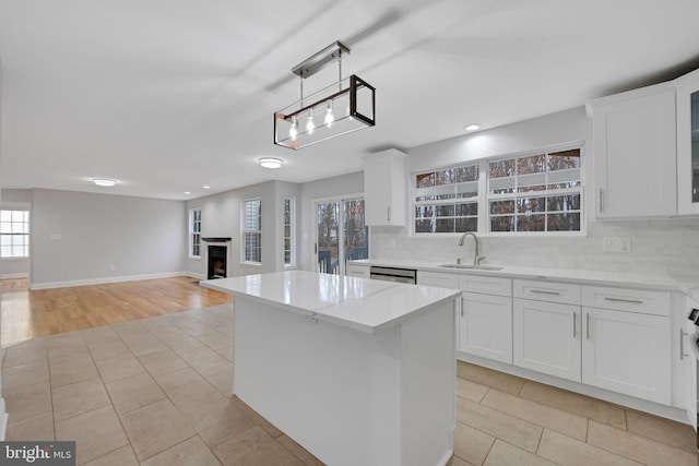 kitchen featuring a sink, a fireplace, light tile patterned floors, decorative backsplash, and dishwasher