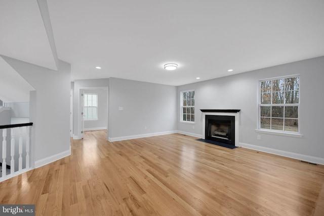 unfurnished living room with visible vents, baseboards, a fireplace with flush hearth, recessed lighting, and light wood-style floors