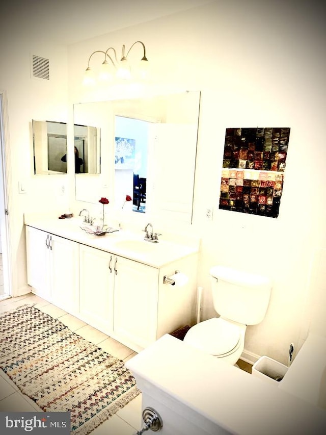 bathroom with visible vents, toilet, double vanity, tile patterned floors, and a sink