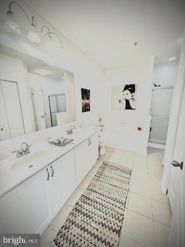 bathroom featuring tile patterned floors, a stall shower, double vanity, and a sink