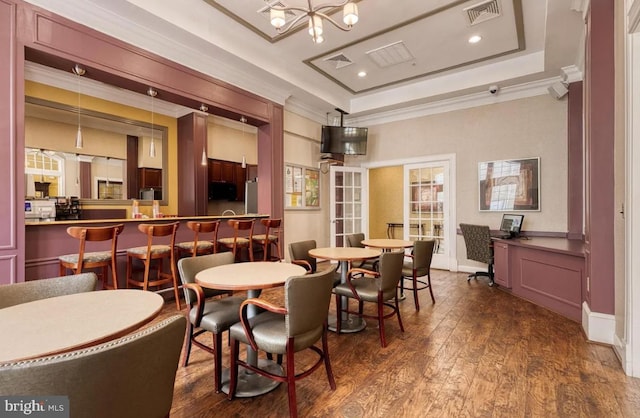 dining area featuring a tray ceiling, visible vents, dark wood-style flooring, and ornamental molding