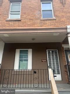 doorway to property with brick siding and a shingled roof