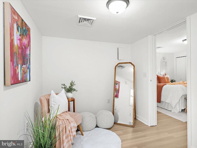 living area with light wood-type flooring, visible vents, and baseboards