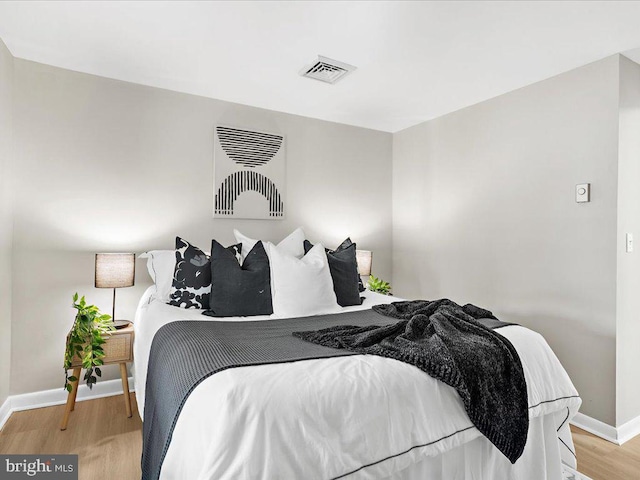 bedroom with visible vents, baseboards, and wood finished floors