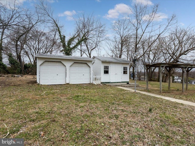 view of front of property featuring a garage, an outbuilding, and a front lawn