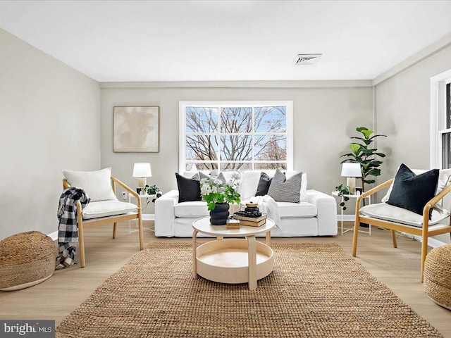 living area featuring visible vents and wood finished floors