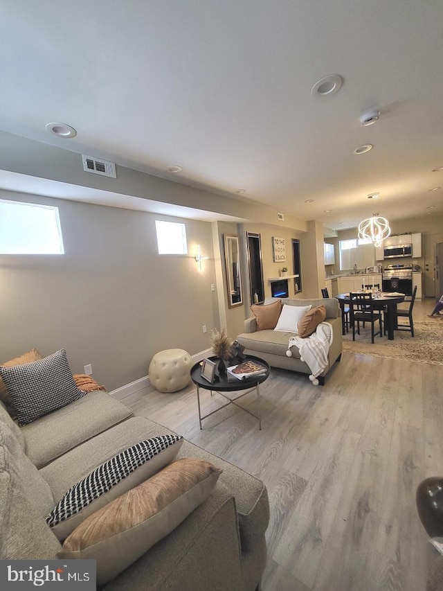 living area featuring light wood-style flooring, visible vents, a chandelier, baseboards, and recessed lighting