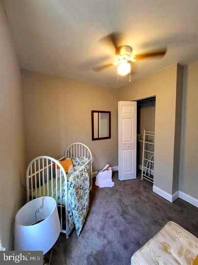 carpeted bedroom with baseboards, a closet, and a ceiling fan
