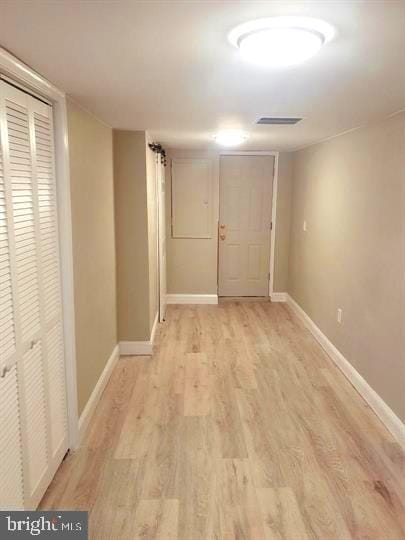 hall with baseboards, visible vents, and light wood-style floors