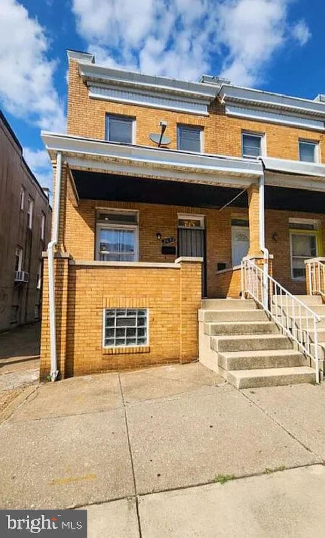 multi unit property with brick siding and a porch