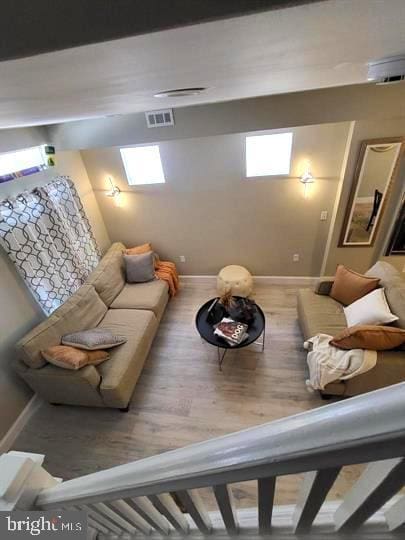 living area featuring baseboards, visible vents, and wood finished floors