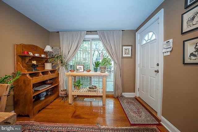 entryway with wood finished floors, visible vents, and baseboards